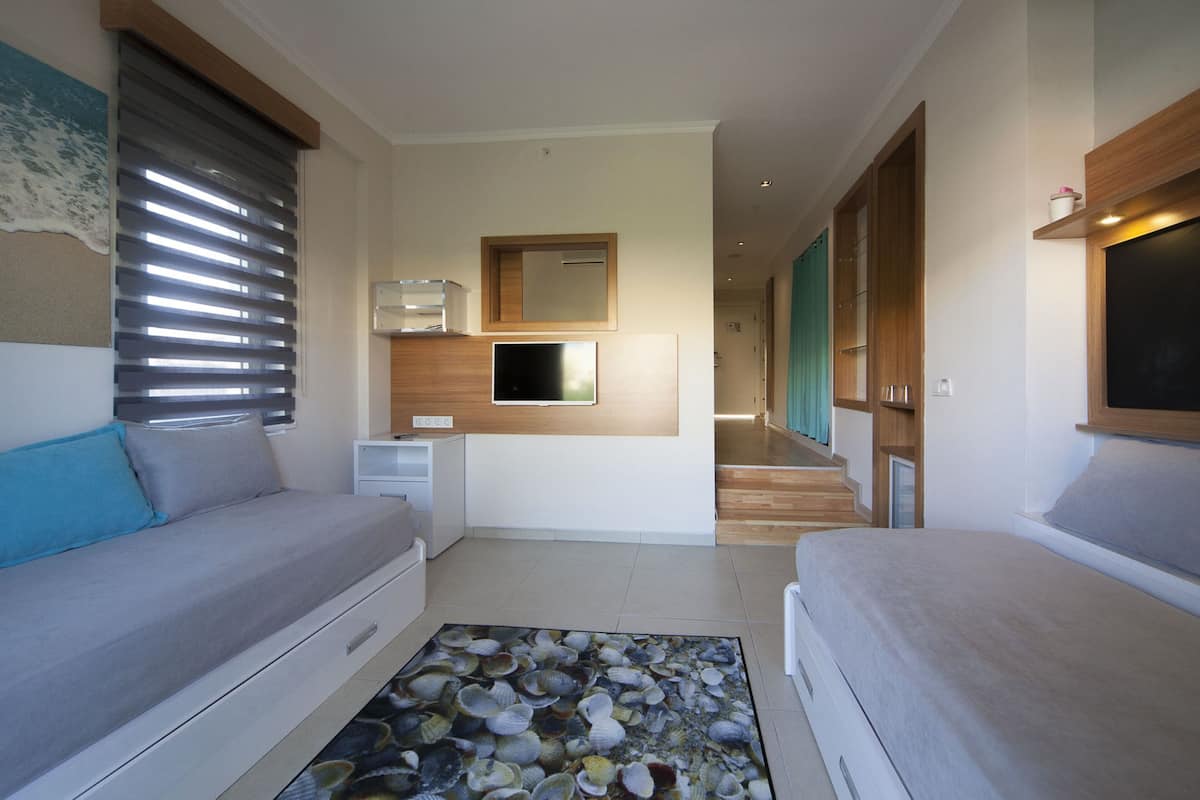 Une pièce moderne et bien éclairée, avec un canapé, un téléviseur, un petit bureau et un tapis à motifs.