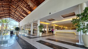 Eine großzügige Lobby mit hoher Decke, großen Fenstern und einer Rezeption.