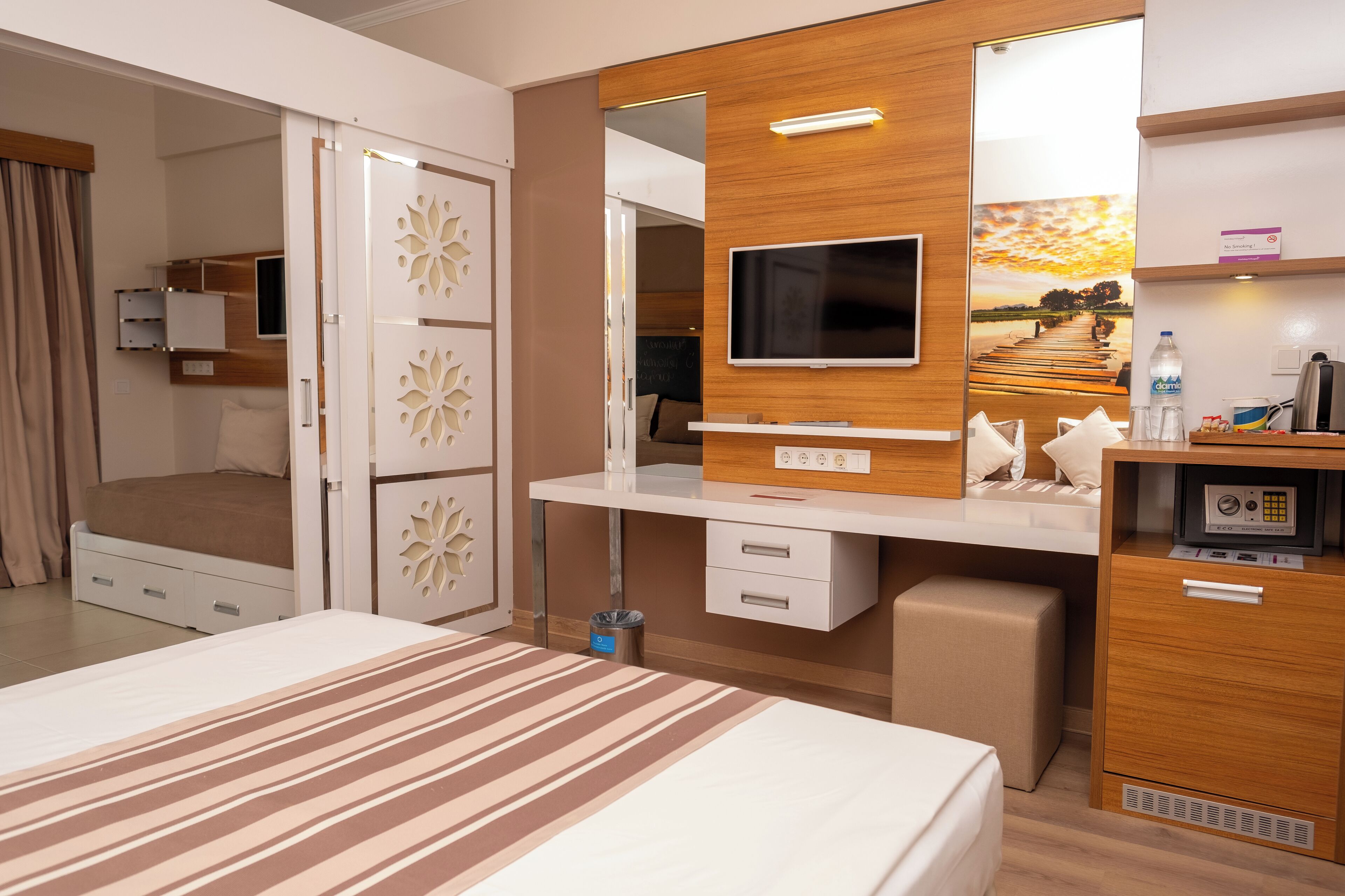 A hotel room with a bed, a TV, a desk, and a wardrobe.