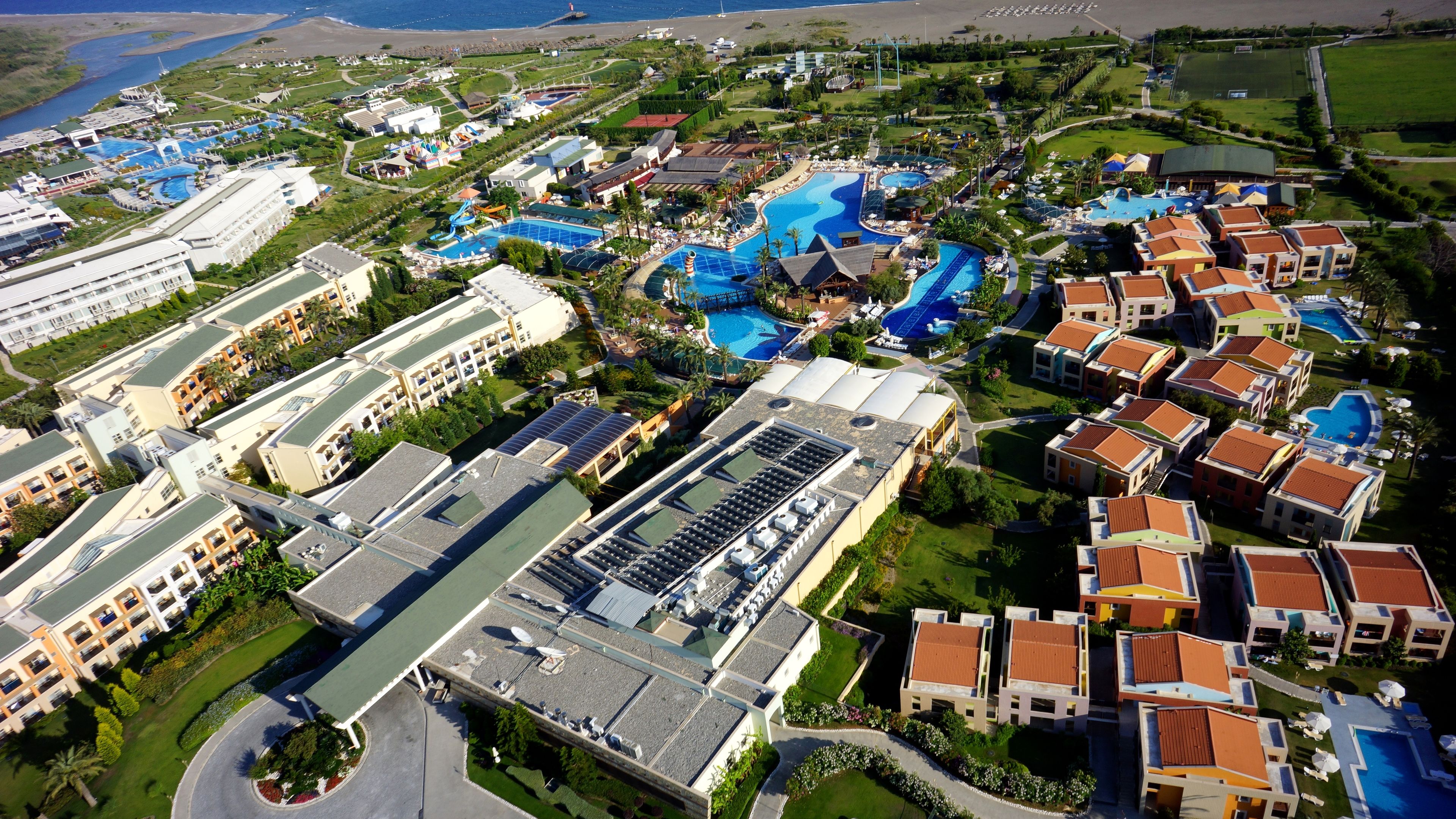 An aerial view of a resort with multiple swimming pools, hotel buildings, and a golf course.