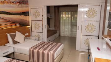 A hotel room with a bed, bedside table, and a desk. There is a view of a sunset through a window.