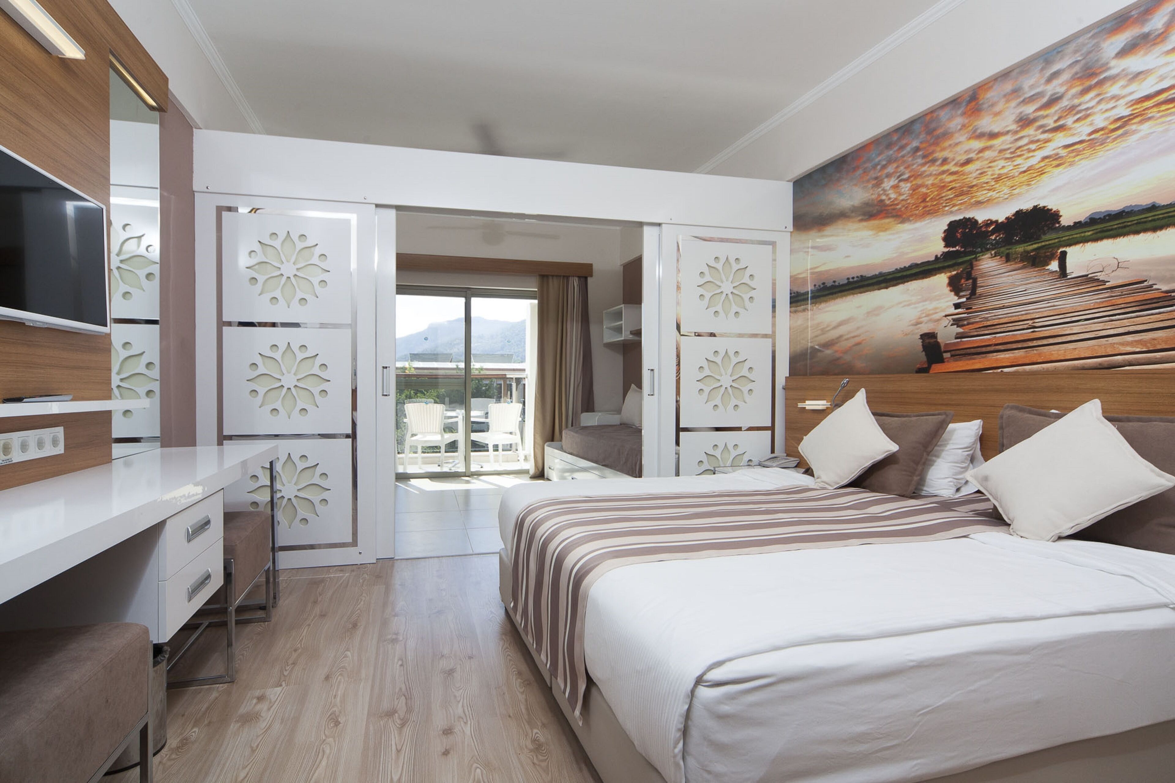 Una habitación de hotel moderna con una cama grande, un escritorio y un televisor.