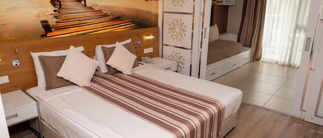 A bedroom with a large bed, a nightstand, a bedside table, a wall-mounted phone, and a window with curtains.