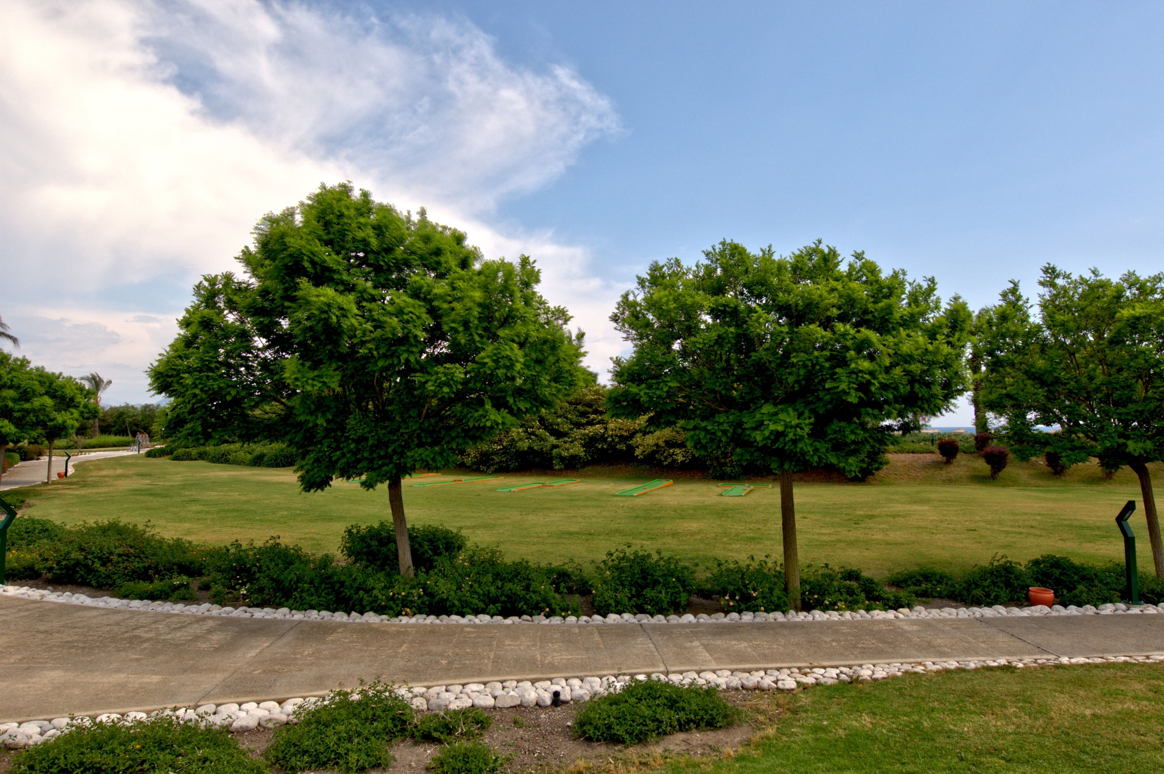 A well-maintained grassy area with trees and a paved walkway.