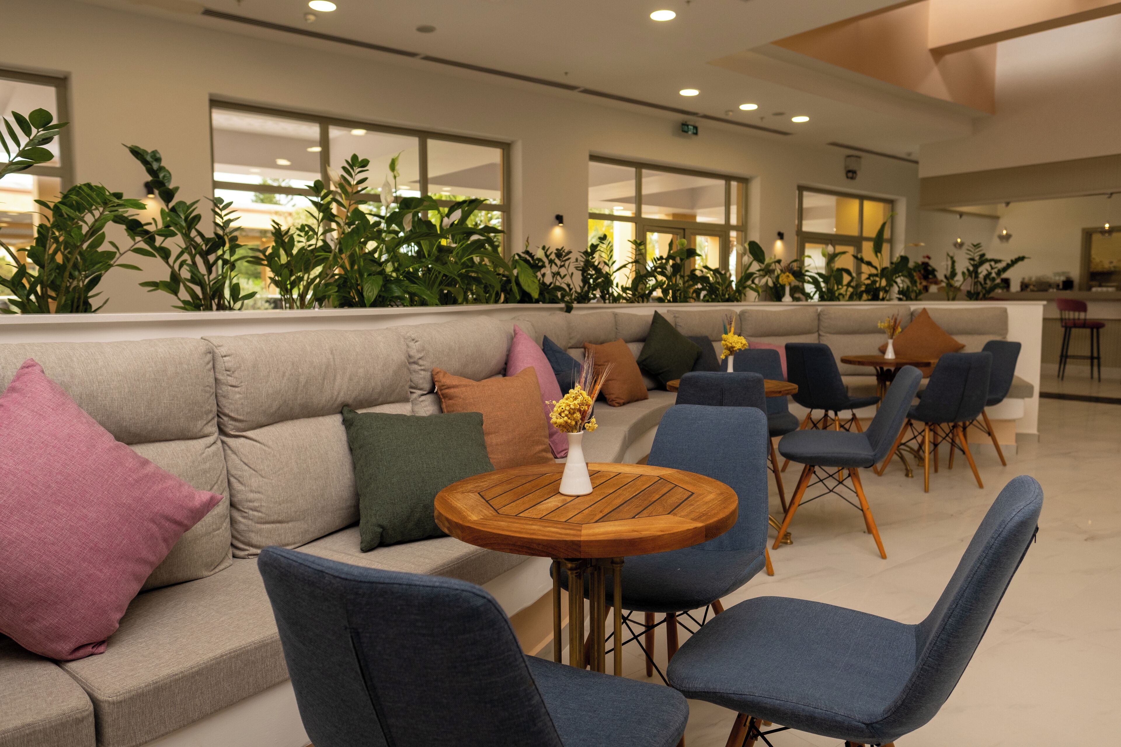 A modern lounge area with a sofa, chairs, and a round wooden table.