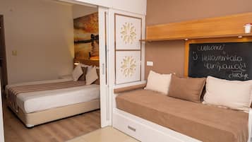 A bedroom with two beds, a wooden headboard, a chalkboard with 'Welcome' written on it, and a painting on the wall.