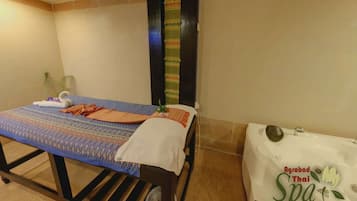 Relax in this serene spa room featuring a comfortable bed and a bathtub, perfect for unwinding.