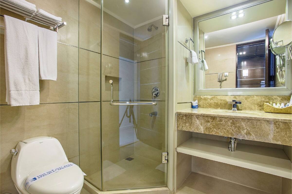 Une salle de bain moderne avec une douche à parois de verre, des toilettes et un meuble-lavabo avec un miroir et un évier.