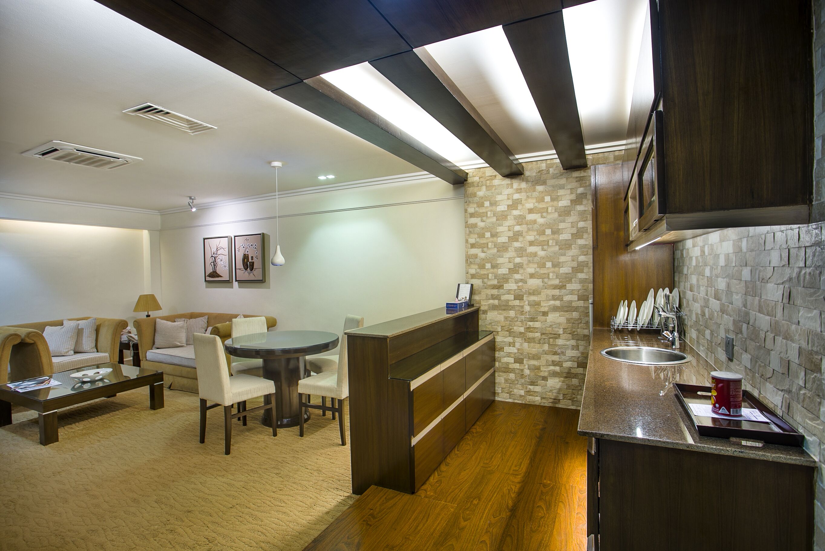 A compact living space with a kitchenette, dining area, and a seating area with a sofa and chairs.