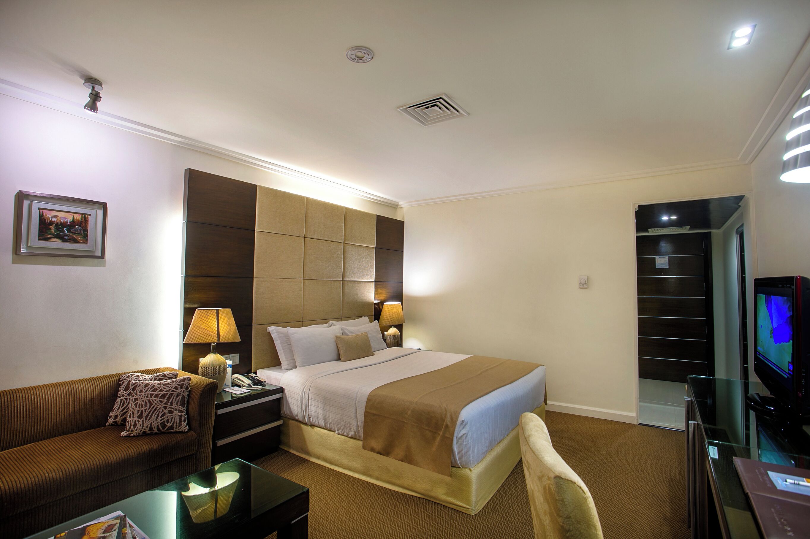 Una habitación de hotel con cama, sofá, escritorio, televisor y estantería.
