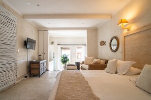A modern bedroom with a large bed, a television, a wicker chair, and a mirror on the wall. - African Violet Guest Suites (Cape Town)