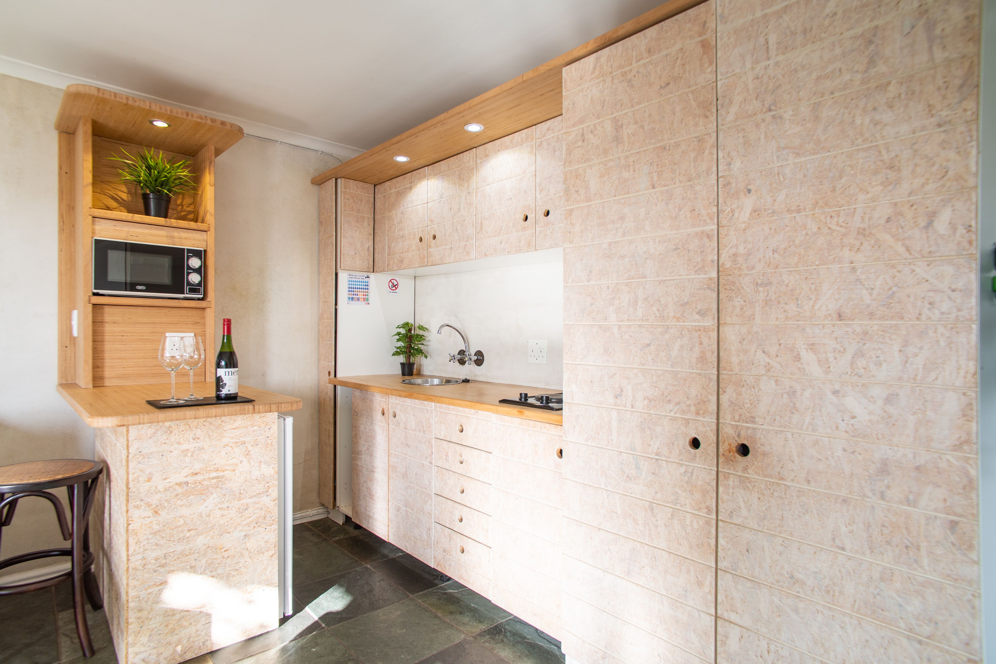 Cocina compacta con microondas, lavamanos y encimera de madera.