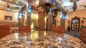 Ein luxuriöses Interieur mit aufwendigen Säulen, einem zentral platzierten, spiegelnden Tisch und traditioneller Einrichtung.