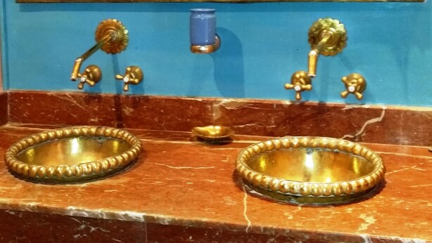 A bathroom with two sinks, each with a decorative bowl, and a blue wall with a faucet and a small blue container. - Riad Puchka (Marrakech)
