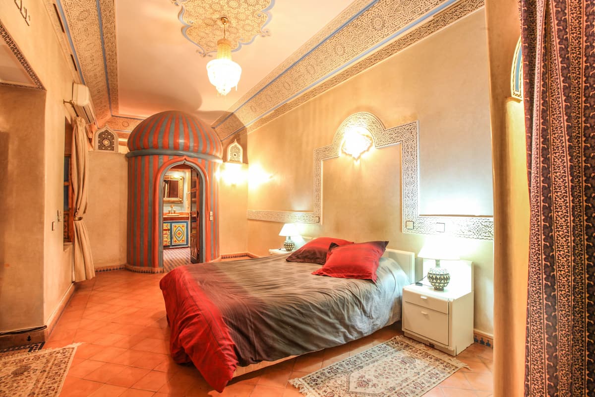 A traditional room with a bed, nightstands, and a decorative mirror.