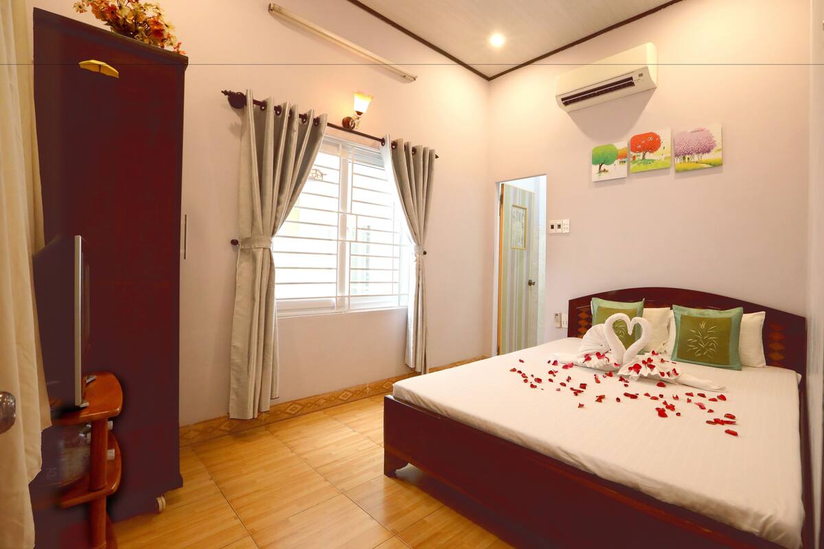 Una habitación de hotel con cama, armario, ventana con cortinas y decoración en la pared.