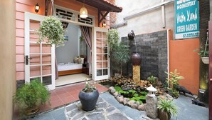 A courtyard with a stone pathway, potted plants, a small pond, and a sign for a green garden. - Green Garden Homestay (Da Nang)
