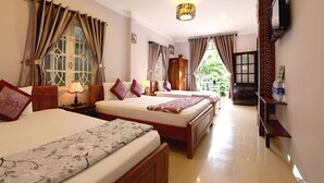 A hotel room with two beds, a TV, a lamp, and a view of greenery outside. - Green Garden Homestay (Da Nang)