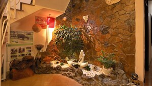 A stone wall with a decorative relief, a large potted plant, and a statue. - Green Garden Homestay (Da Nang)