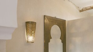 A bathroom with a sink, a mirror, and a wall-mounted light fixture.