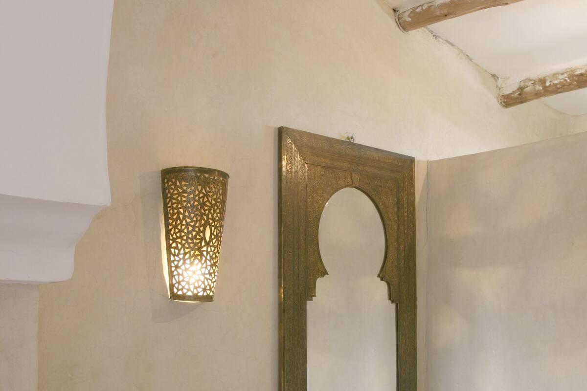 A bathroom with a sink, a mirror, and a wall-mounted light fixture.