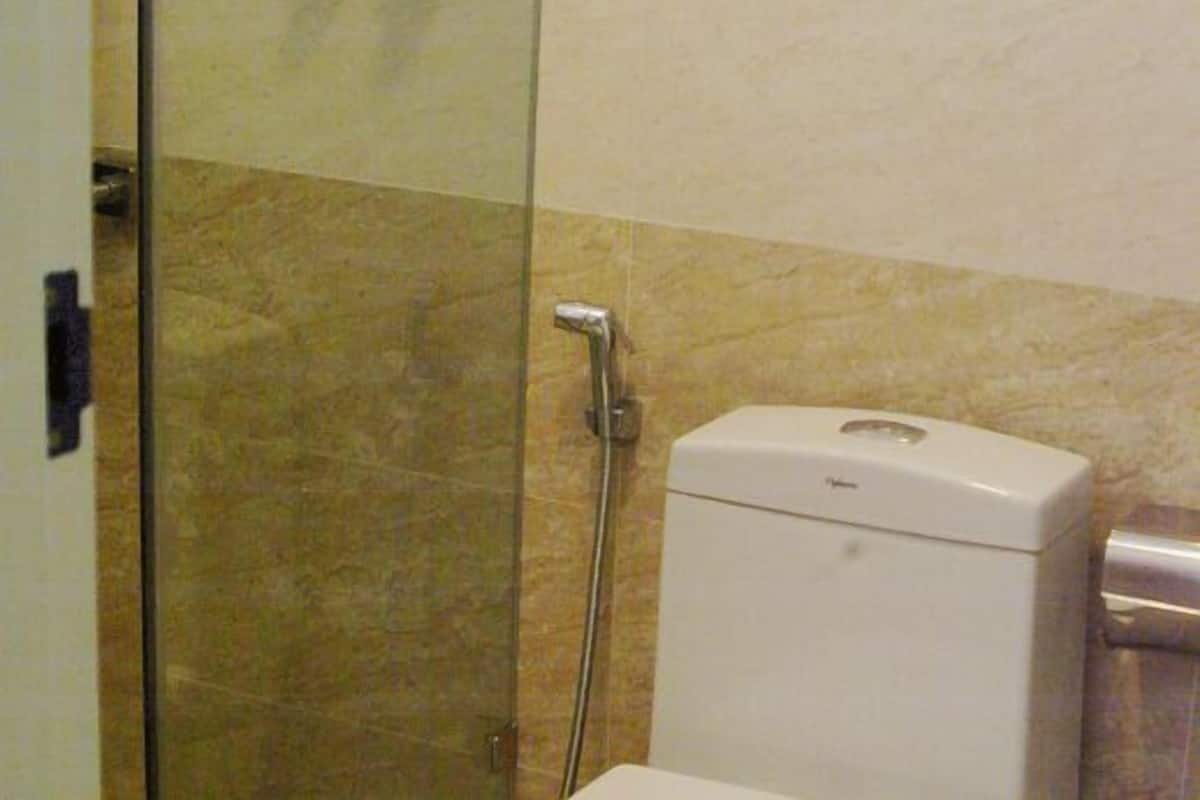Un baño con cabina de ducha de vidrio, inodoro y dispensador de toallas en la pared.