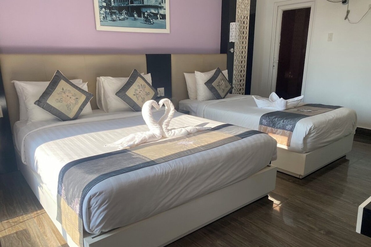 Una habitación de hotel con dos camas, un cabecero y un cuadro enmarcado en la pared.