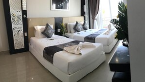 A hotel room with two beds, a black console table, a decorative wall panel, and a window with curtains. - Mui Ne Sports Hotel (Mui Ne)