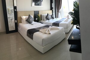 A hotel room with two beds, a black console table, a decorative wall panel, and a window with curtains.