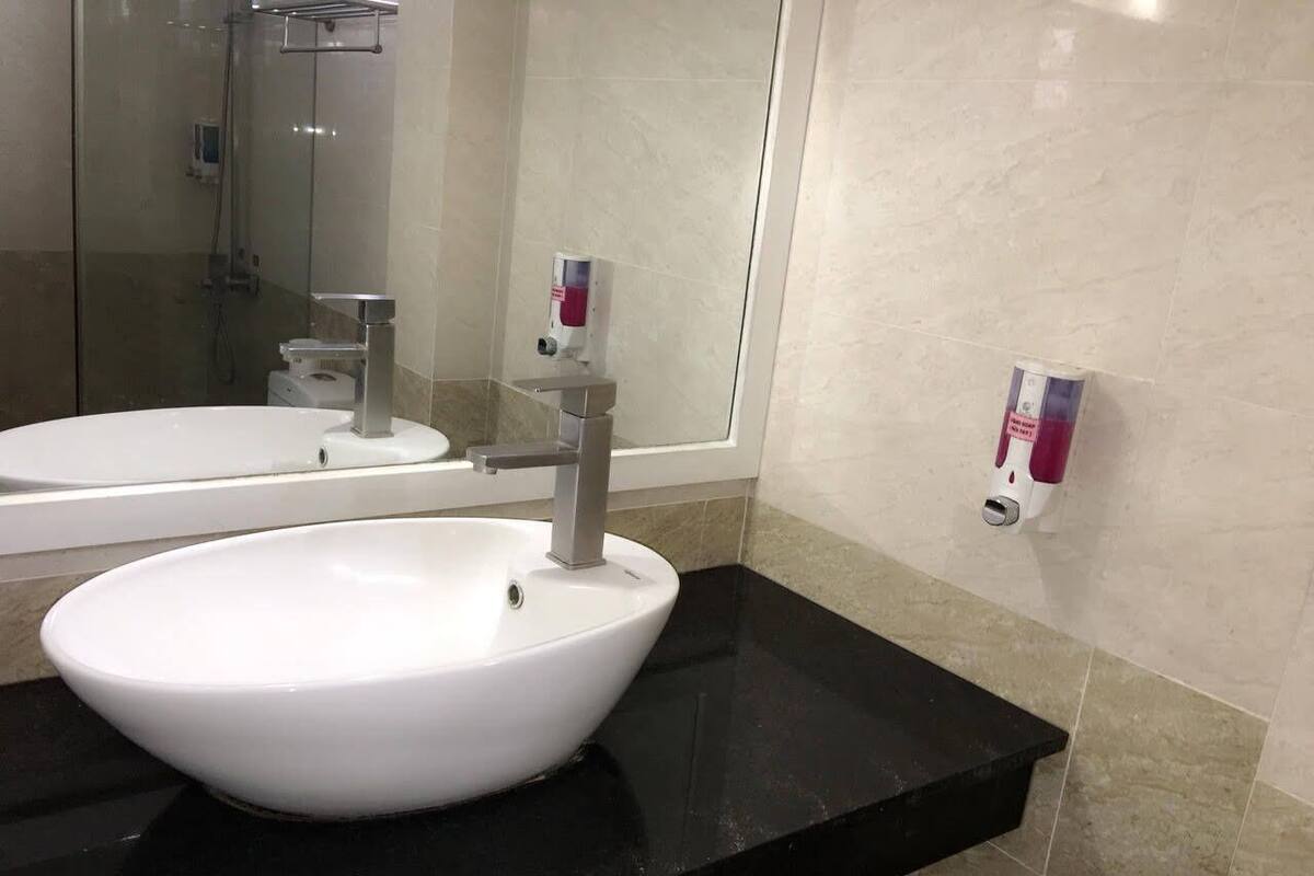 Un baño con un lavabo blanco, una encimera negra y un espejo.