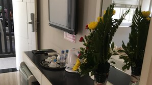 A hotel reception desk with a black counter, a small potted plant, a water bottle, a cup, and a tray with a small dish. - Mui Ne Sports Hotel (Mui Ne)