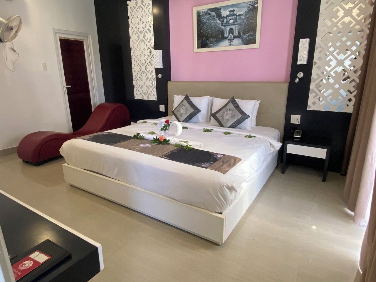 Een moderne slaapkamer met een groot bed, een rode stoel en een wandlamp.