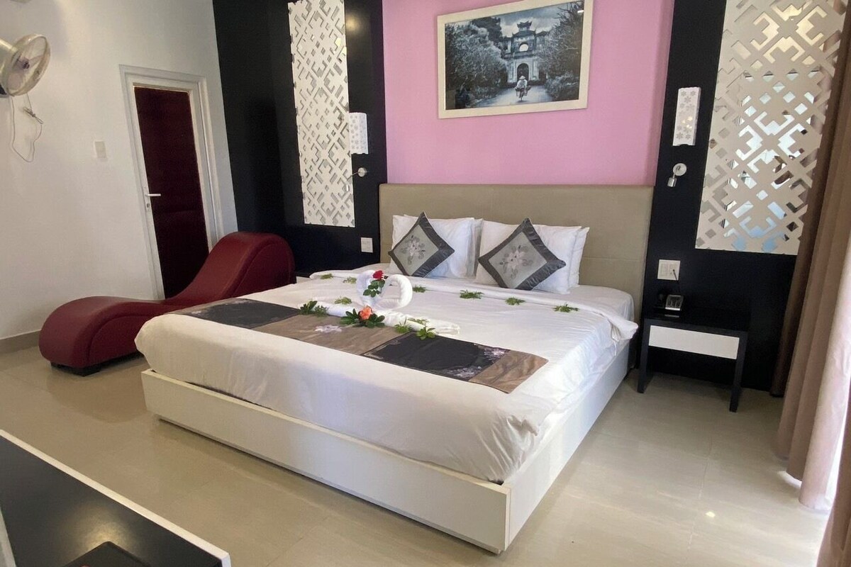 Un dormitorio moderno con una cama grande, una silla roja y una lámpara de pared.