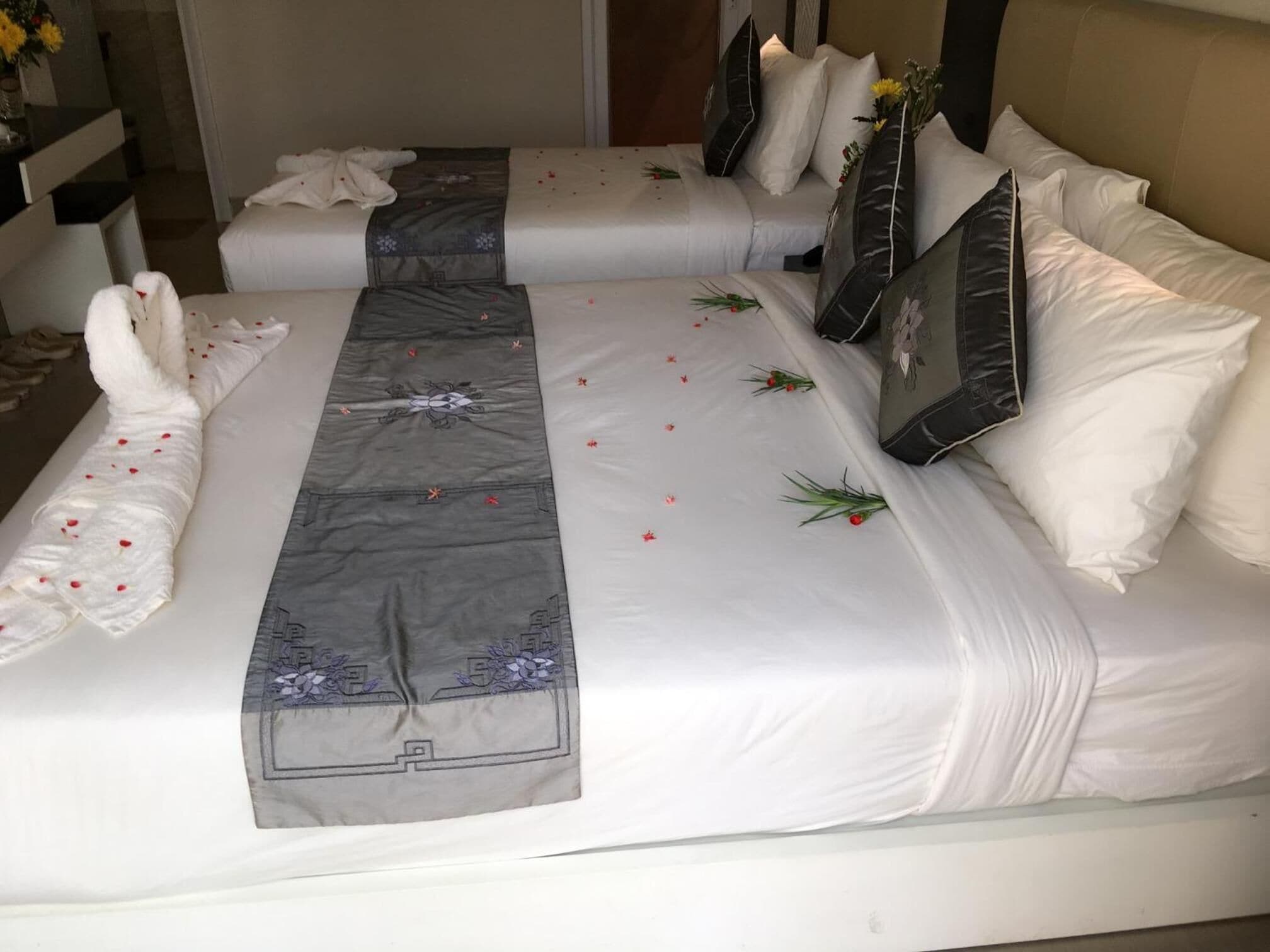 Habitación de hotel con dos camas, cada una con ropa blanca y almohadas decorativas.