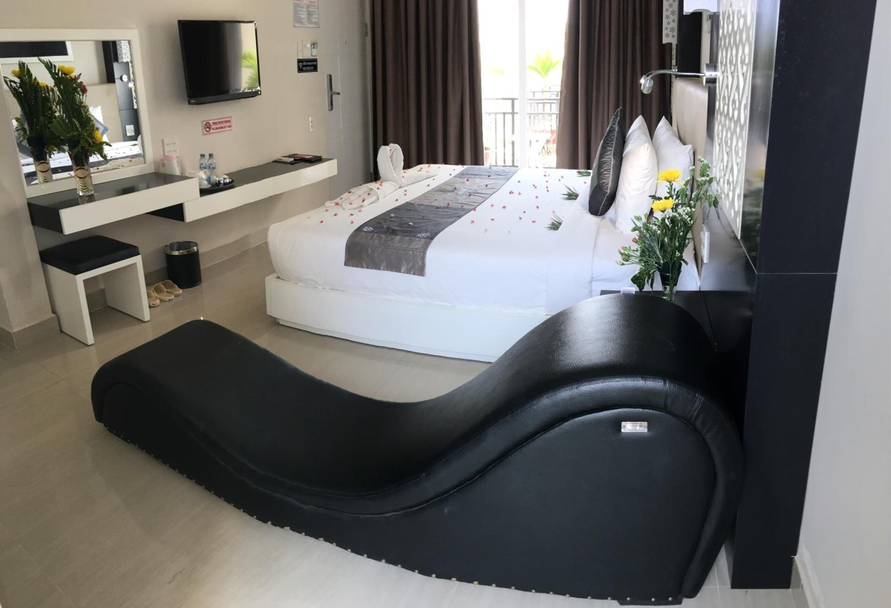 A modern hotel room with a bed, a desk, a TV, and a massage chair.