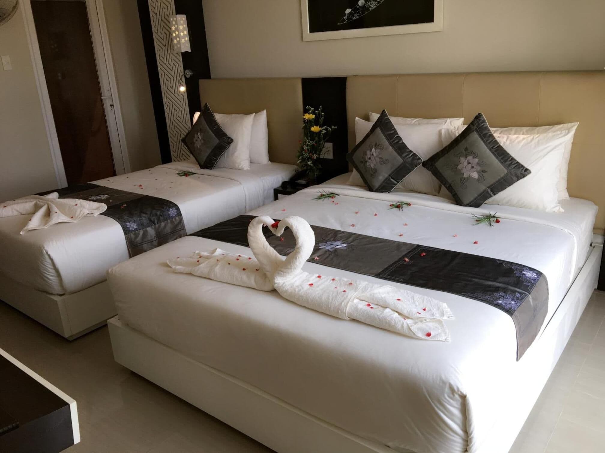 A hotel room with two beds, each with white bedding and decorative pillows.