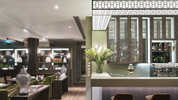 Un moderno espacio de bar con barra, taburetes y un jarrón decorativo con flores.