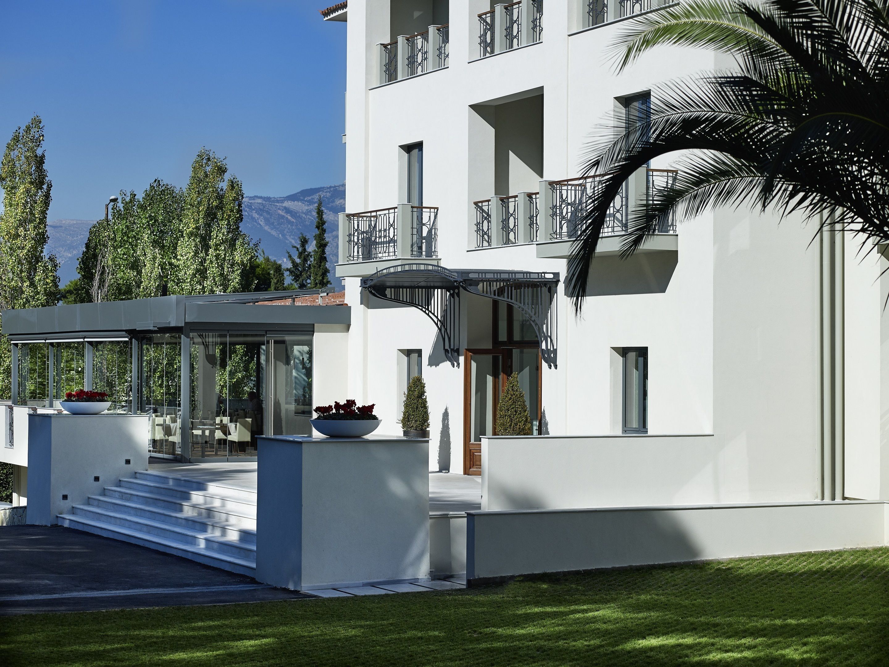 Un edificio moderno de varios pisos con fachada blanca, balcones y un área de estar exterior cubierta.