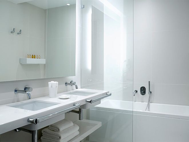 A modern bathroom with two sinks, a bathtub, and a large mirror.