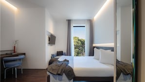 Una habitación de hotel moderna con una cama grande, un escritorio, una silla y un televisor.