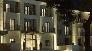 Un hotel de varios pisos con balcones, una entrada central y fachada de piedra.