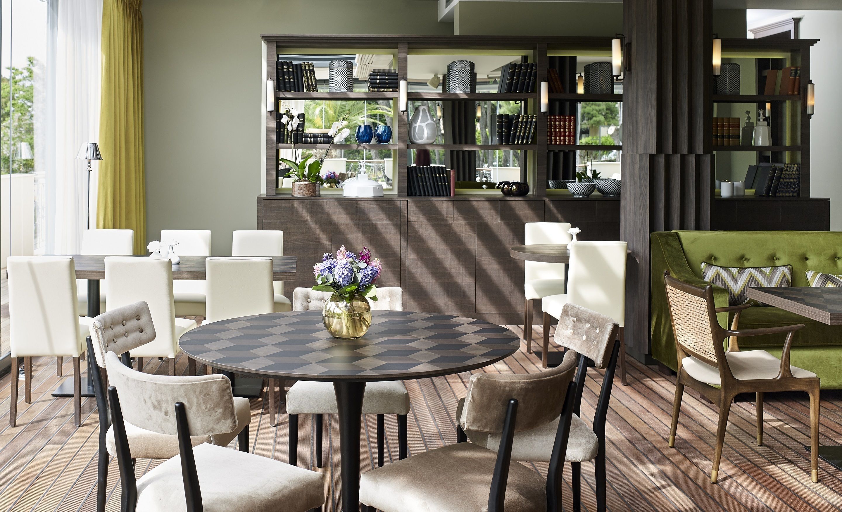 Un coin repas avec une table ronde, des chaises blanches et un jeu d’échecs en guise de décoration centrale.