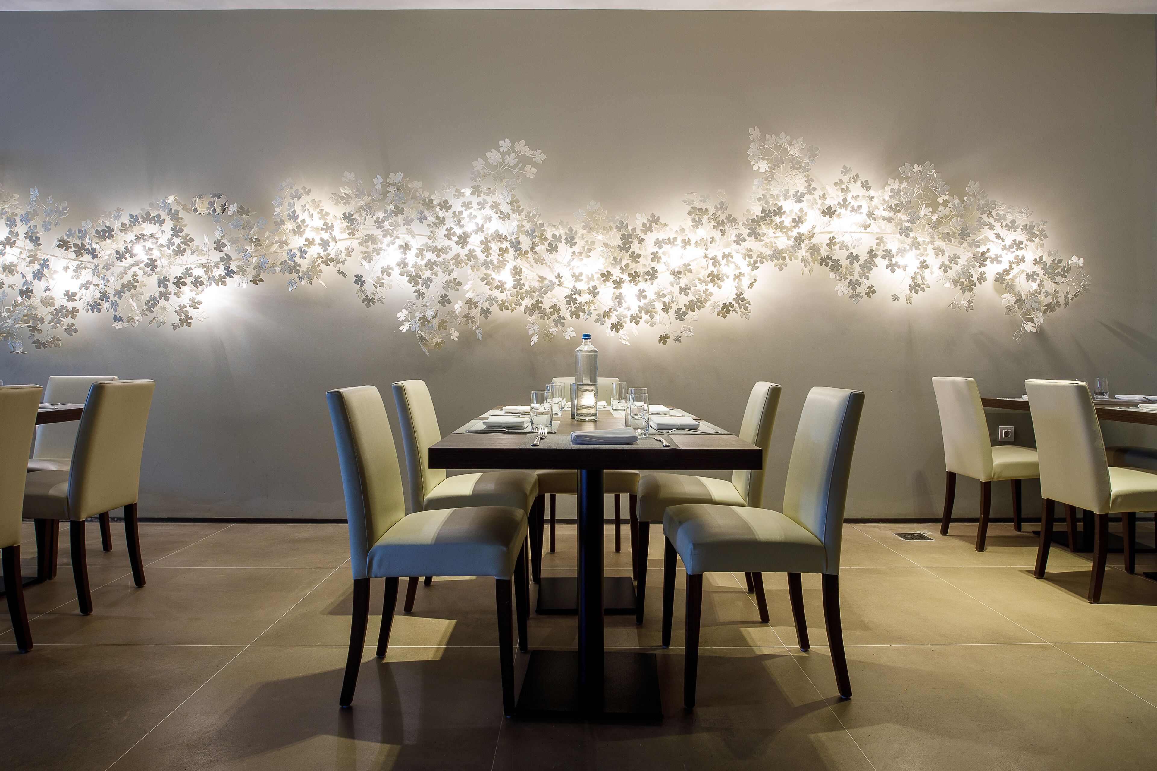 A dining area with a table set for four, surrounded by chairs, and a decorative wall with floral patterns.