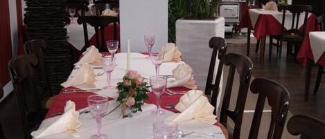 A dining table set with pink wine glasses, white napkins, and a centerpiece of pink flowers.