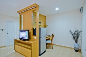 A compact kitchen with a built-in refrigerator, a microwave, and a wooden counter.