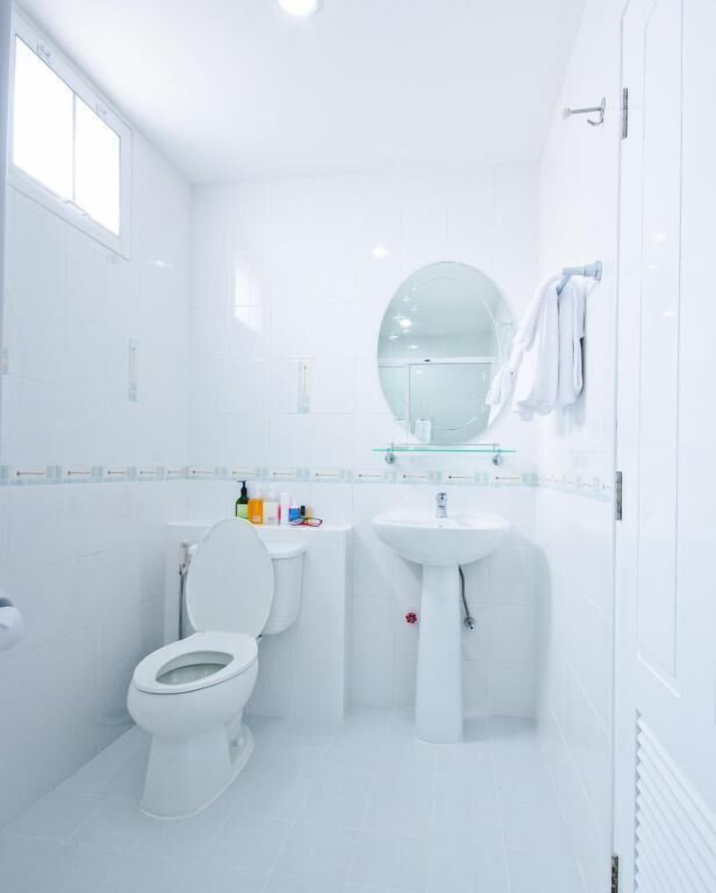 Een moderne badkamer met toilet, wastafel en spiegel.