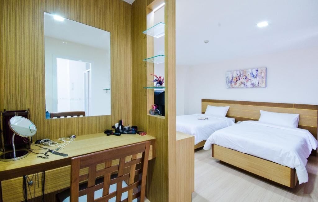 Ein Hotelzimmer mit einem Holztisch, einem Spiegel, einem Bett und einem Bild an der Wand.