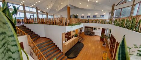 A spacious, multi-level interior with wooden flooring, a central staircase, and a mezzanine level.