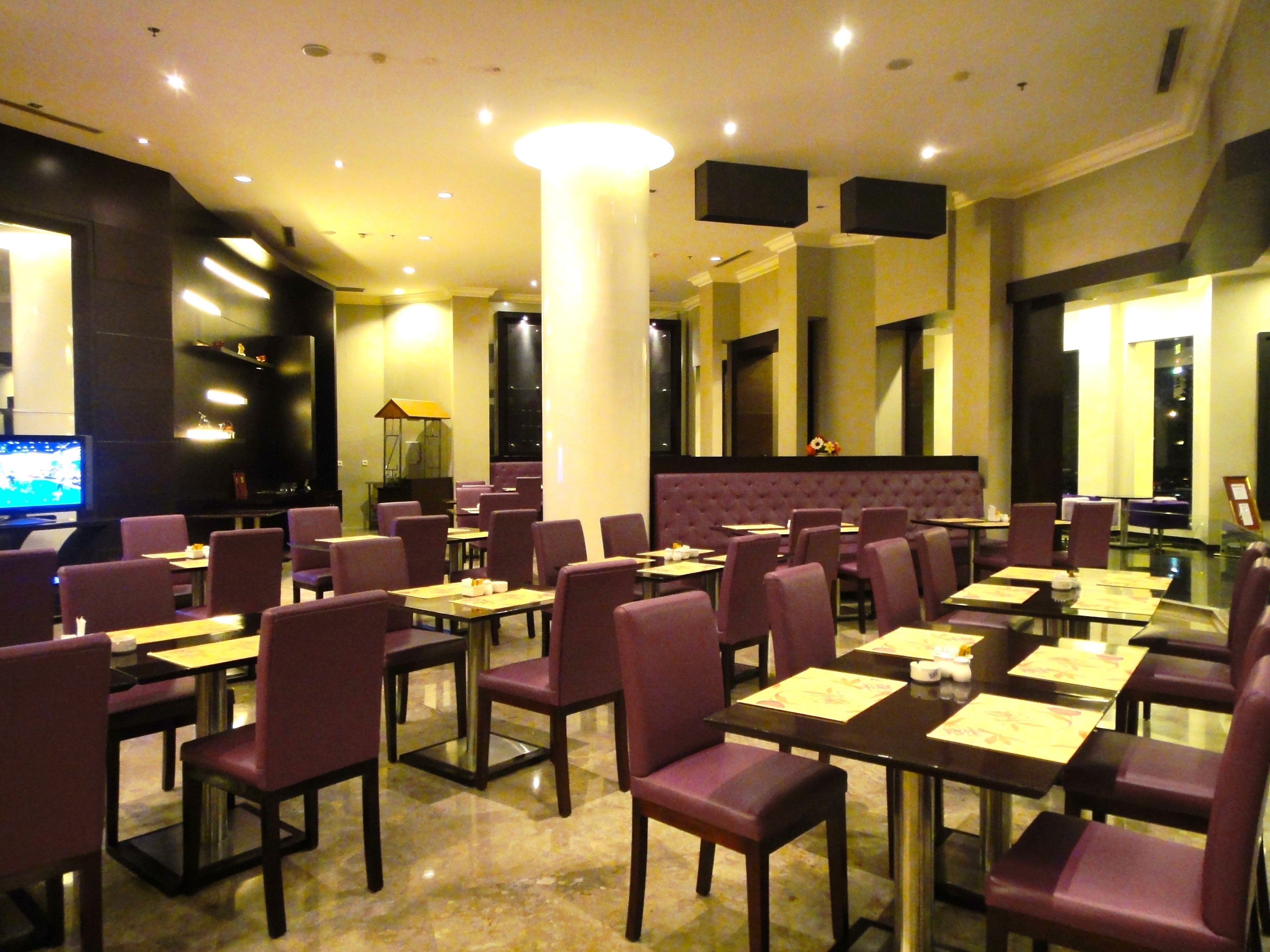 A restaurant with tables and chairs, a television, and a bar area.