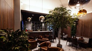 A modern lounge area with leather seating, a bar, and a large tree.